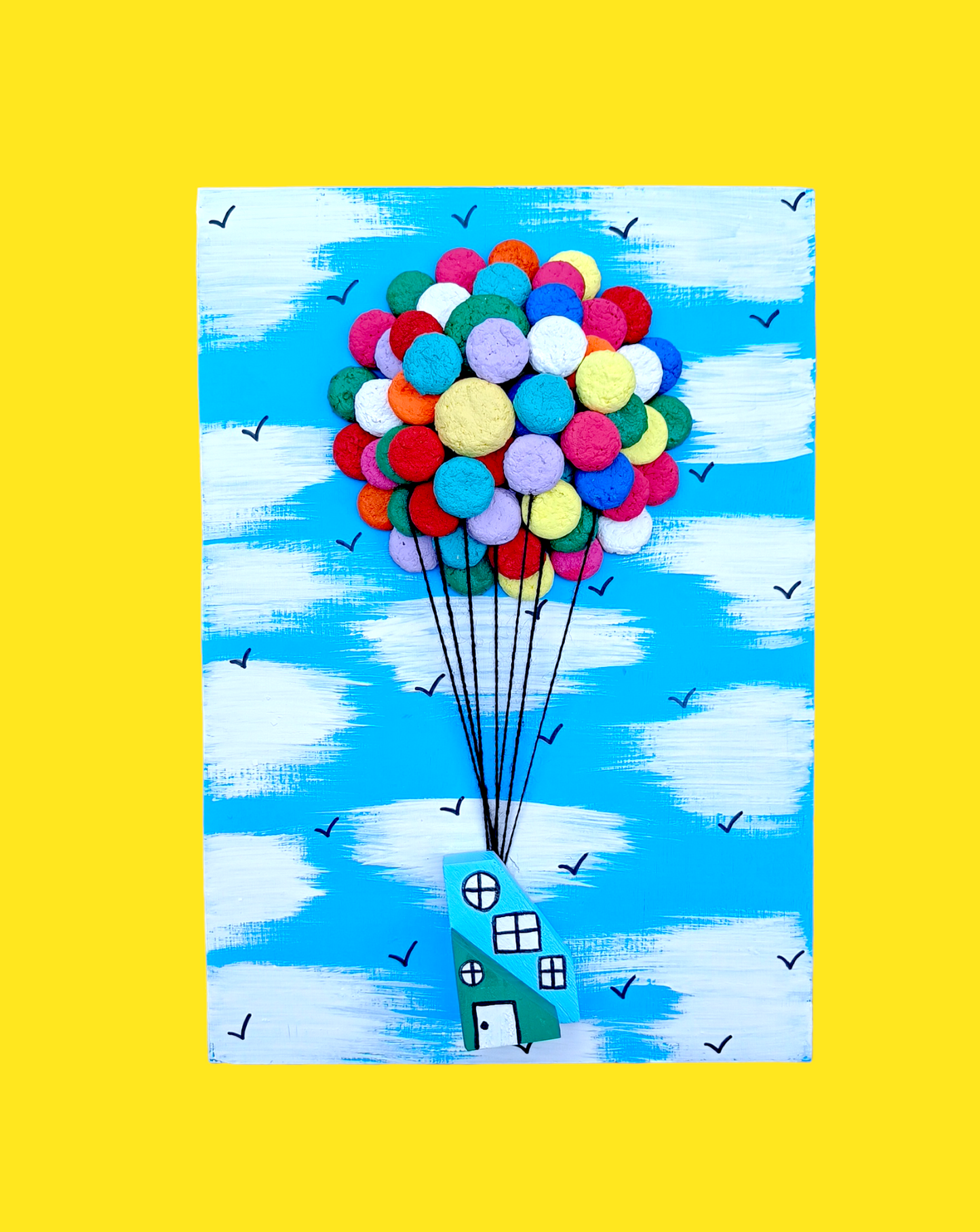 Craft Kit of Bright coloured balloons floating house against light Blue sky with birds flying
