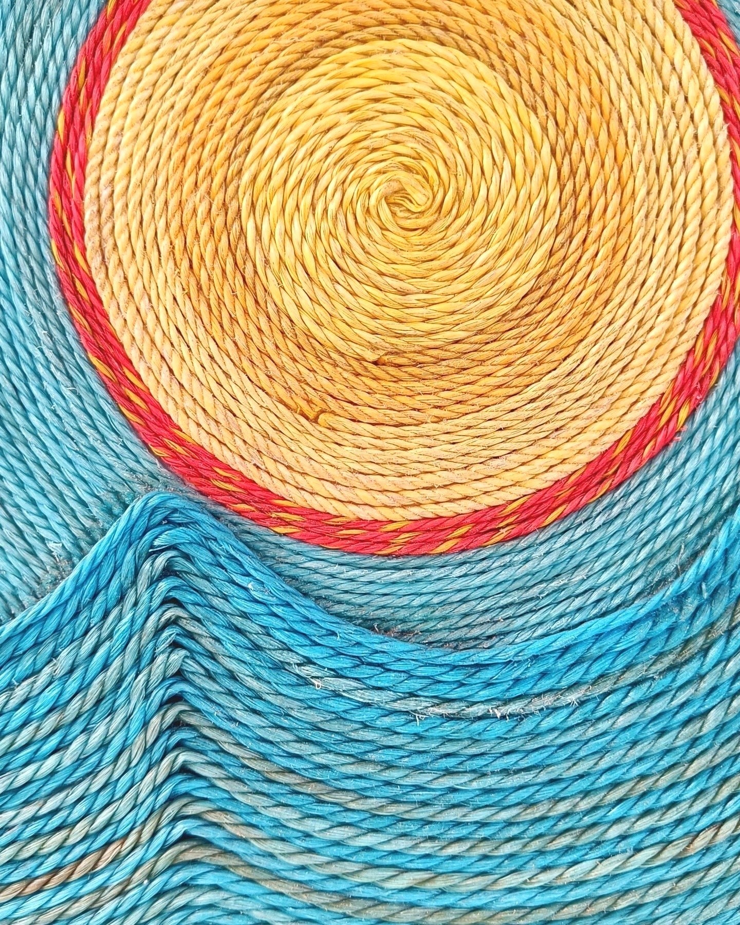 Close-up of colorful fishing net with a blue, yellow, and red spiral pattern.