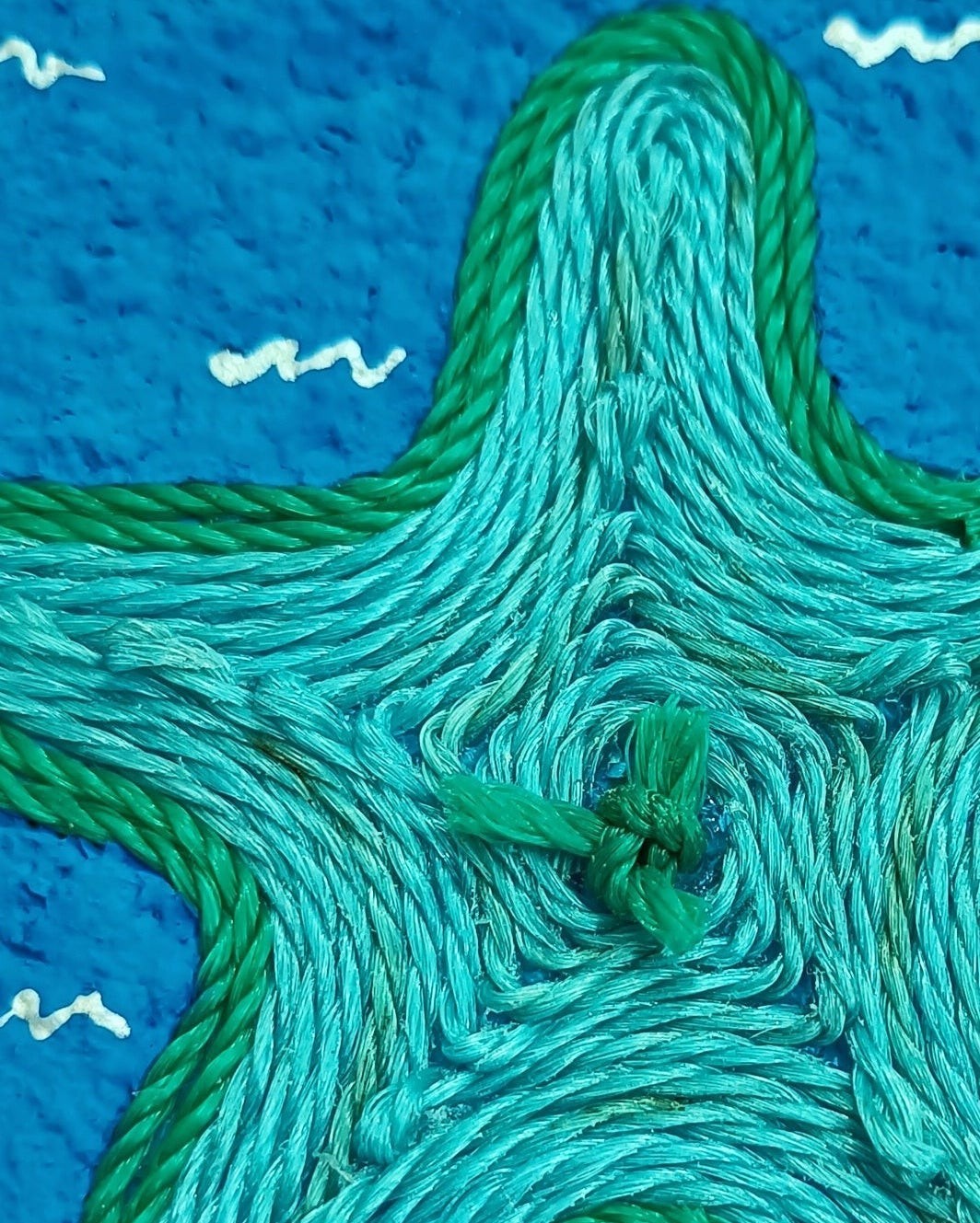 Green and blue fishing net starfish on a blue textured paper mache background